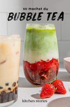 two glasses filled with bubble tea and strawberries next to each other on a table