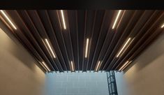 the ceiling is made up of wood slats and has lights coming from underneath it