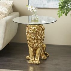 a glass table with a gold lion sitting next to a white couch in a living room