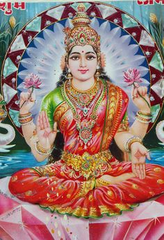 the hindu goddess sitting in lotus position with her hands clasped up and holding two flowers