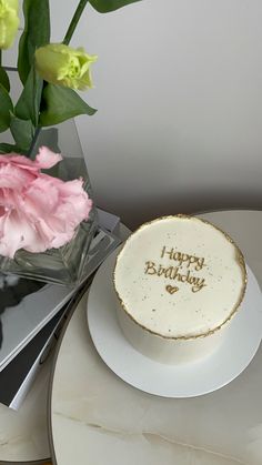 a birthday cake sitting on top of a table next to a vase filled with flowers