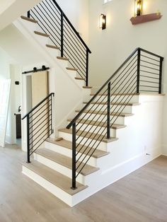 a white staircase with black handrails and wood flooring in an empty house