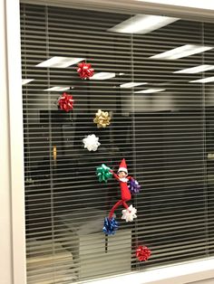 an office window decorated with christmas decorations and tinsels for the elf in the window