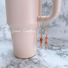 a coffee cup with two charms hanging from it's side next to a mug