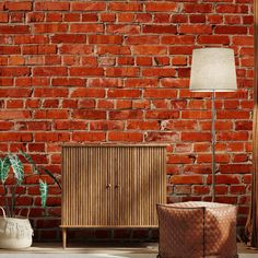 a red brick wall with a wooden cabinet next to it and a lamp on the side