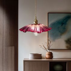 a pink lamp hanging over a wooden cabinet