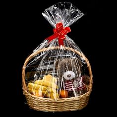 a basket filled with lots of food on top of a black table next to a red bow