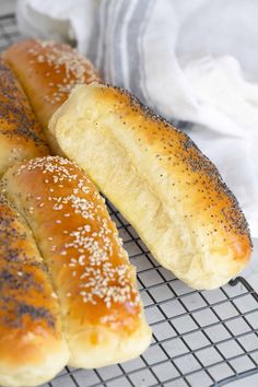 three loaves of bread sitting on a cooling rack next to each other, with sesame seeds sprinkled all over them