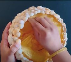 a person holding up a yellow plate with shells on it's sides and hands