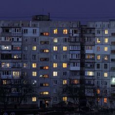 an apartment building with many windows lit up in the dark night time, at dusk