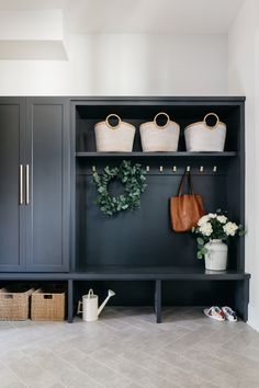 an entryway with blue cabinets and white flowers on the shelf, two purses hanging from hooks