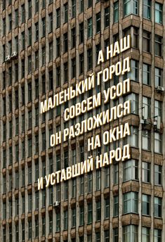 a tall building with many windows and words written on the side in different languages,