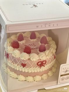 a pink cake with white frosting and strawberries in a box