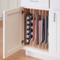 an open cabinet with various items in it on top of a hard wood floored floor