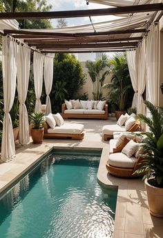 an outdoor living area with couches and plants next to a swimming pool in the backyard