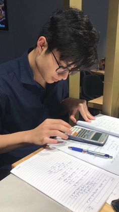 a young man sitting at a desk using a calculator