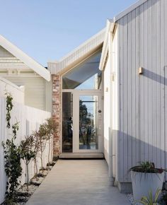 a white house with an entry way leading to the front door and side yard area