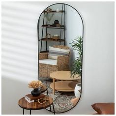 an oval mirror in the corner of a living room with furniture and decor on it