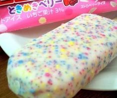 an ice cream sandwich with sprinkles is on a plate next to a candy bar