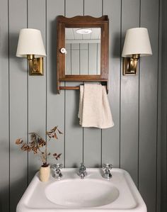 a white sink sitting under a bathroom mirror next to two light fixturees on a wall