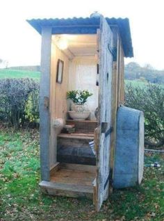 an outhouse with the door open and steps up to it's outside area