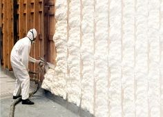 a man in white coveralls spray painting a wall