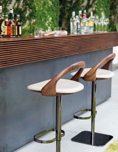 two bar stools sitting next to each other in front of a counter with bottles on it