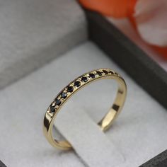 a gold ring with black diamonds sits in a box