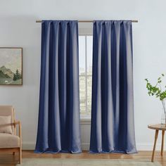 a living room with a chair and window covered in blue drapes next to a painting