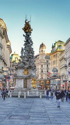 people are walking around in the middle of a busy city square with many buildings on either side