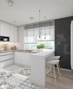 a kitchen with a chalkboard wall and white cupboards, counter tops, and stools