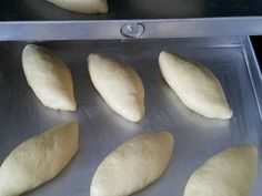 six uncooked breads sitting on top of a metal pan