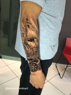 a man's arm with a ship tattoo on it