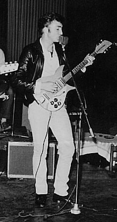 a man standing in front of a microphone while playing an electric guitar