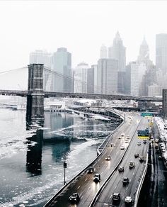 cars are driving on the road in front of a large bridge and city skylines