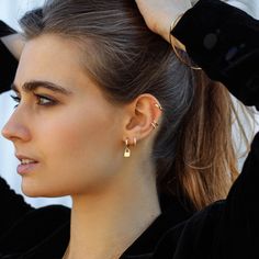 a woman with her hair in a ponytail and wearing gold ear climbrs on top of her head