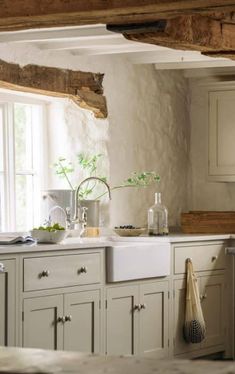 a kitchen filled with lots of white cupboards and counter top next to a window