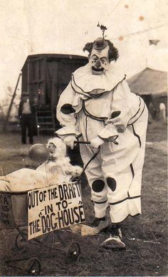 an old photo of a clown pushing a baby in a wagon with a sign on it