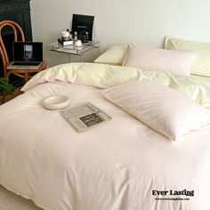 a bed with white sheets and pillows on top of it next to a table filled with books