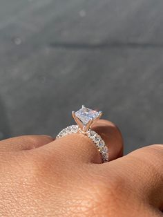 a woman's hand with a diamond ring on top of her finger and an engagement band in the middle