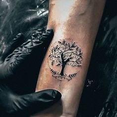 a person with a tattoo on their arm is holding up a hand that has a tree on it