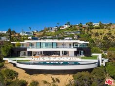 an aerial view of a modern home on the hillside with swimming pool and lounge chairs