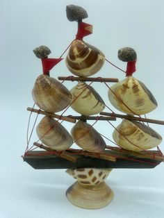 a small ship made out of seashells on a white background with red strings