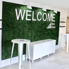 a welcome sign is on the wall behind two stools