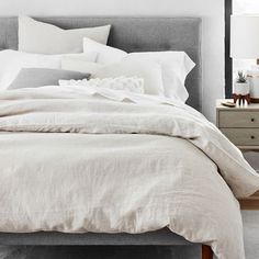 a bed with white linens and pillows in a bedroom