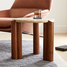 a small table with a glass on it in front of a chair and remote control