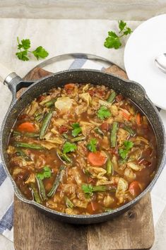 a pot filled with soup sitting on top of a wooden cutting board