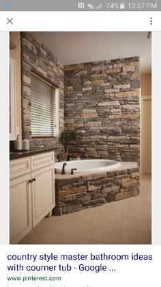 a bathroom with a stone wall and white tub in the corner next to a sink