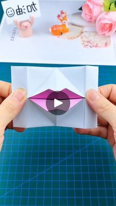 someone is holding an origami piece with pink lips on it and the video below