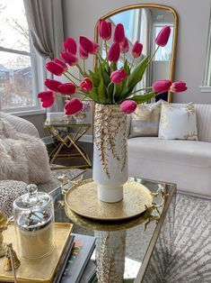 a vase filled with pink flowers sitting on top of a table next to a couch